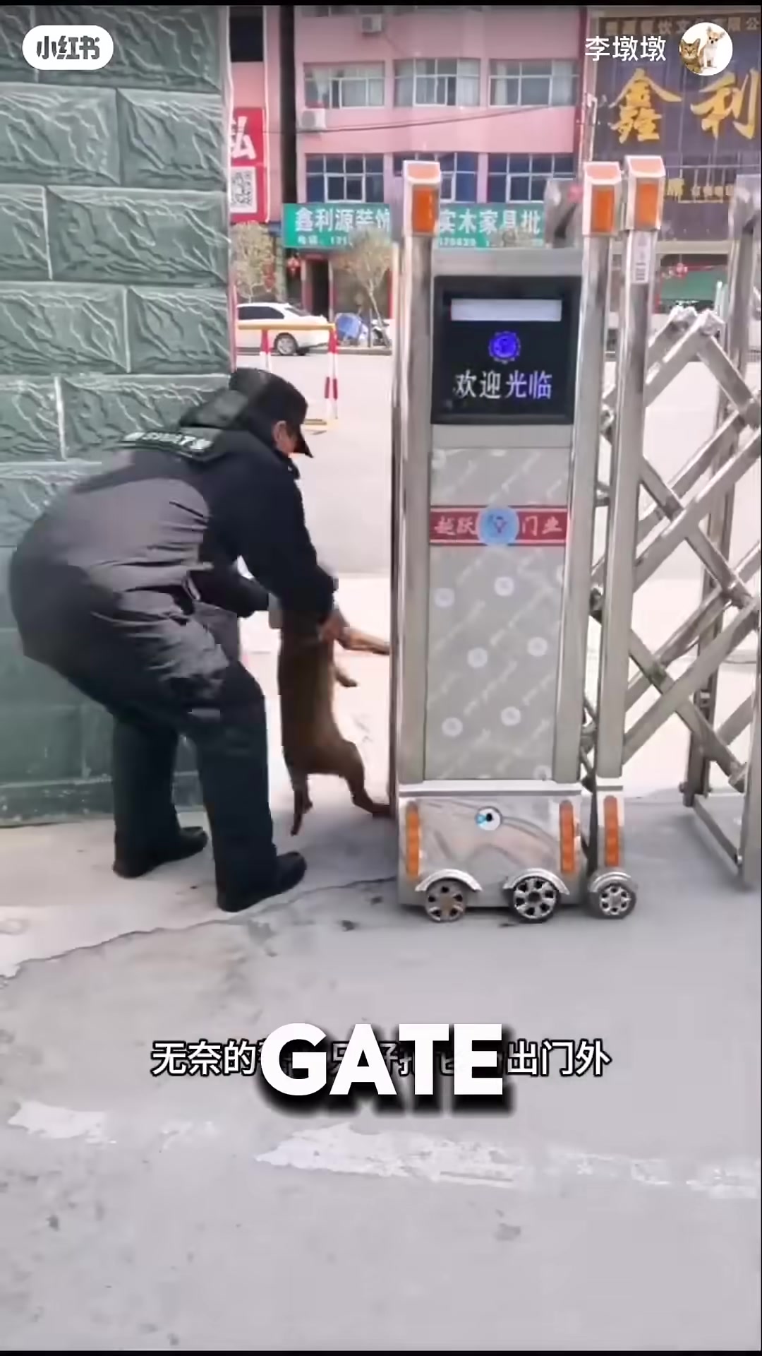A police officer gently carries a determined puppy out of the station gate.