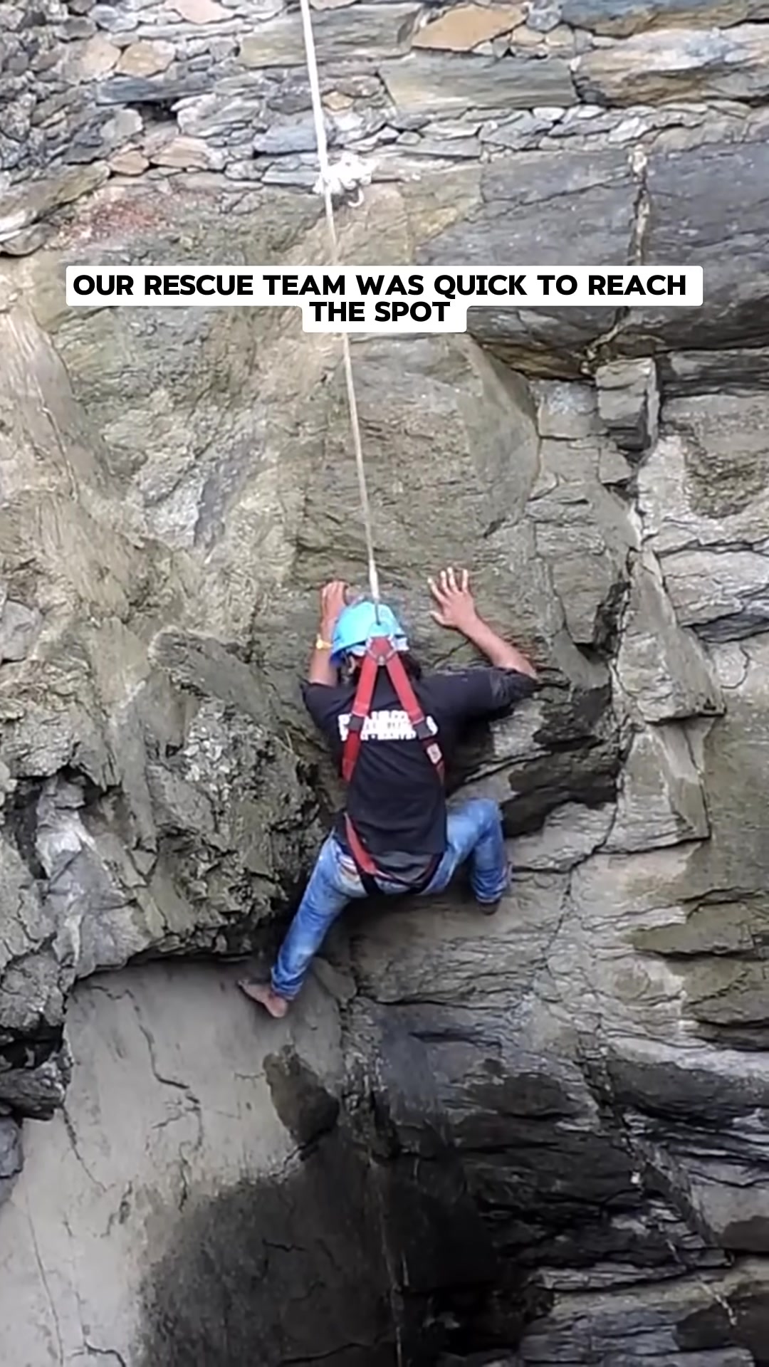 A rescuer in a harness is being lowered into the well by a rope, with other people watching from above.