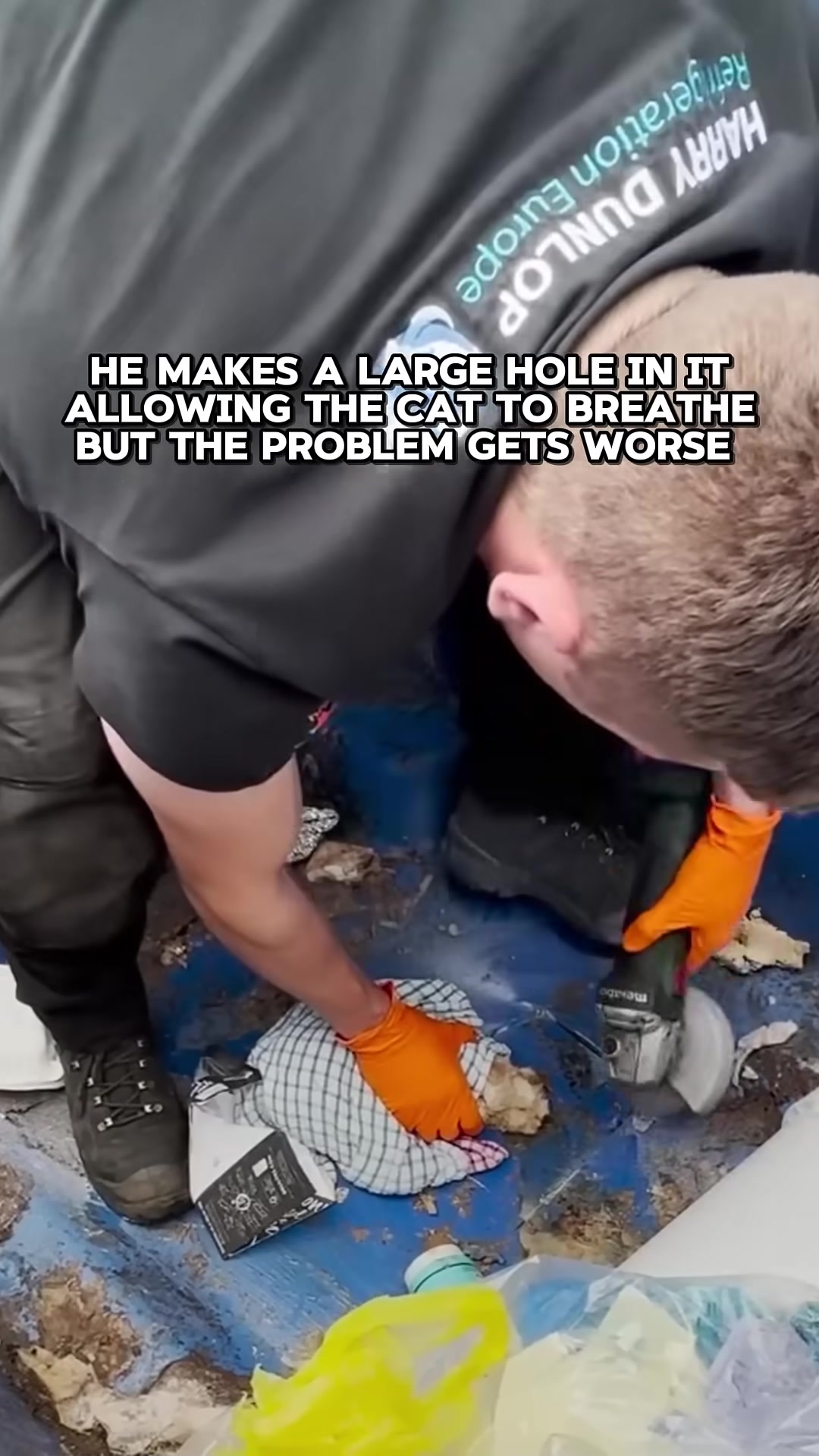 The engineer carefully cuts a large hole in the dumpster while the kitten is still trapped.
