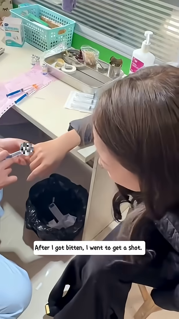 A person's arm receiving an injection, with medical supplies in the background.