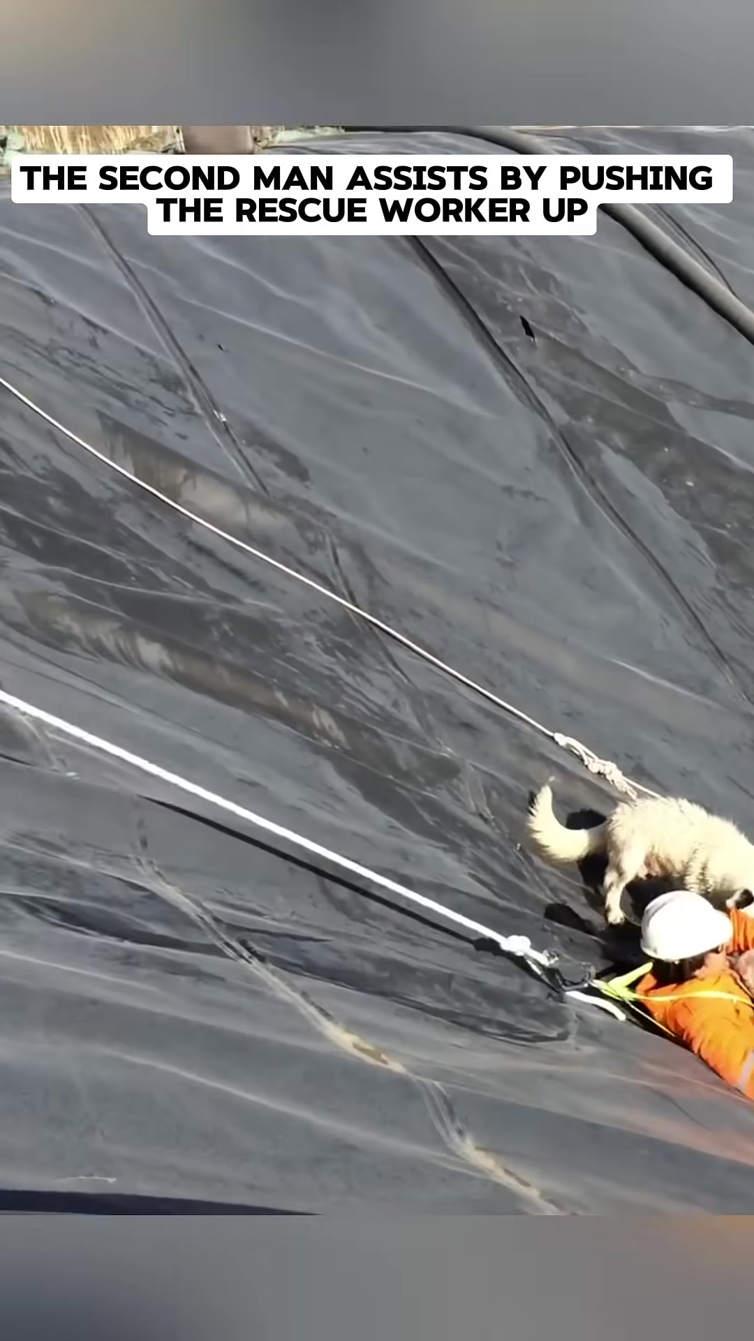 Two men are pulling a rope, one of them is assisting the other who is on a steep slope.