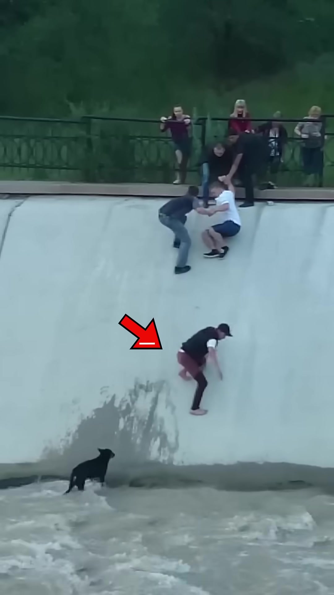 Multiple men forming a chain, reaching down the wall to help.