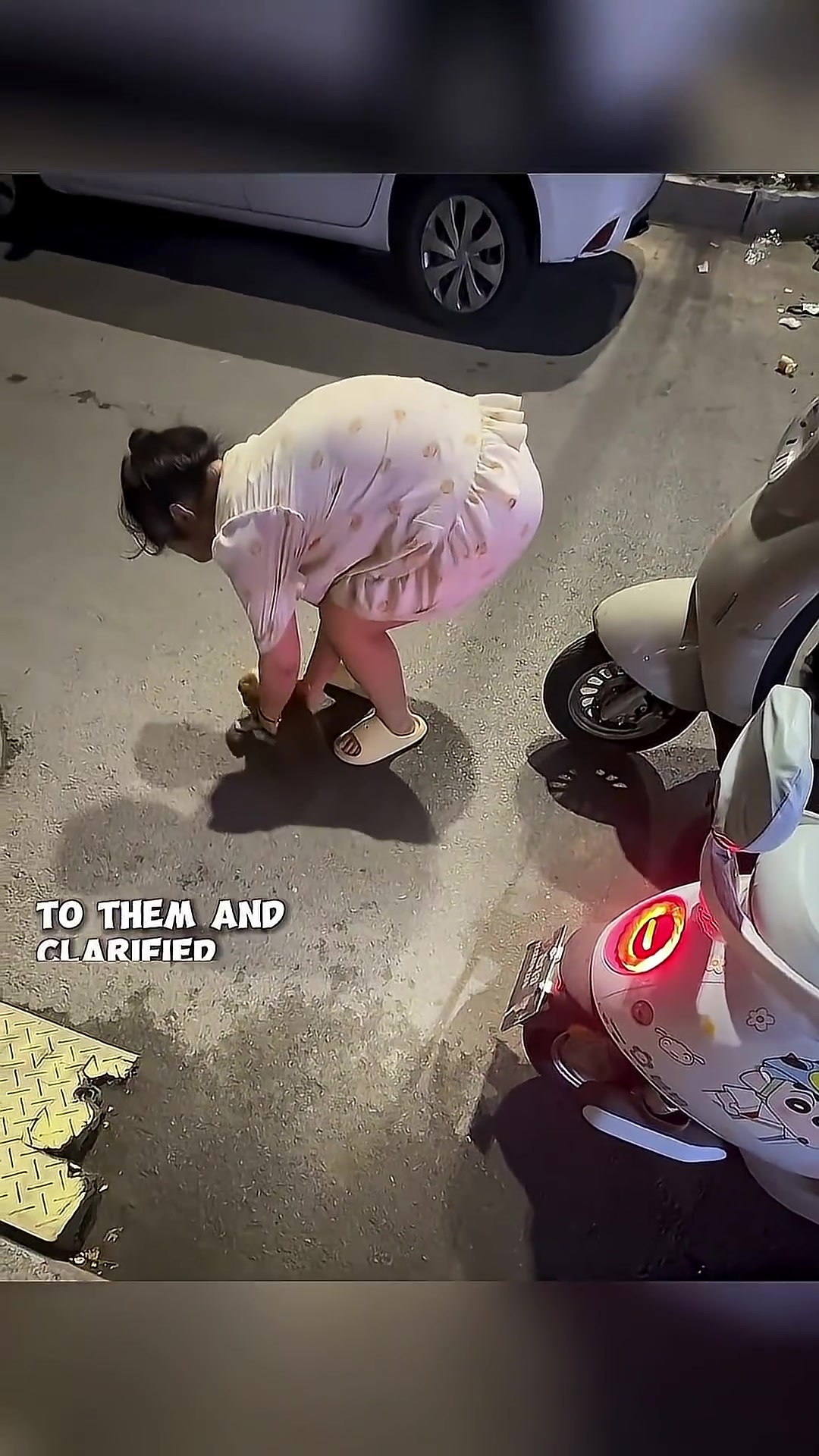 A woman is holding a puppy, and a man is talking to another person near a scooter.