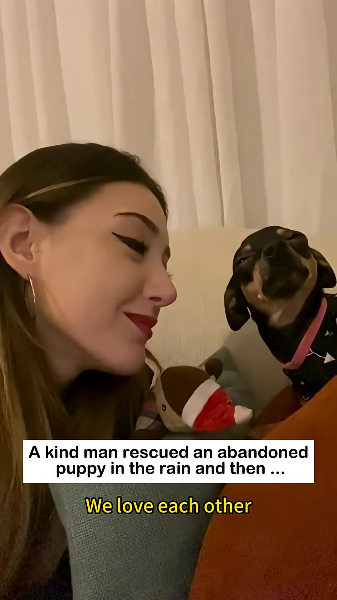 A woman gently kisses a puppy on the nose.