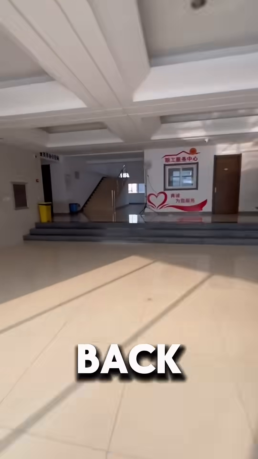 A hand opens a door, revealing an office hallway with chairs and a desk.