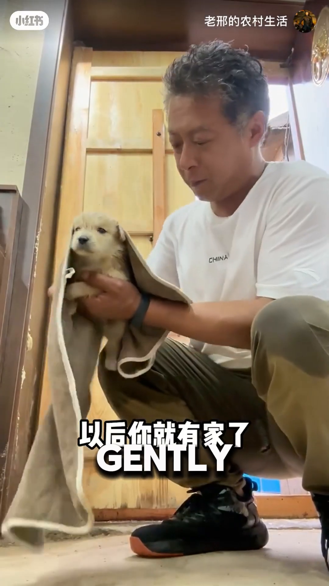 A man is gently drying a small puppy with a towel.